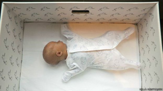Un bebé duerme en una caja de cartón.