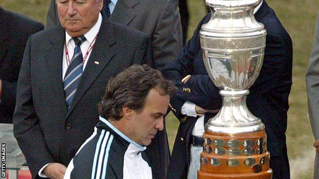 Marco Bielsa pasa frente al trofeo de la Copa América.