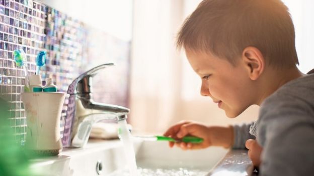 Un niño lavando su cepillo de dientes