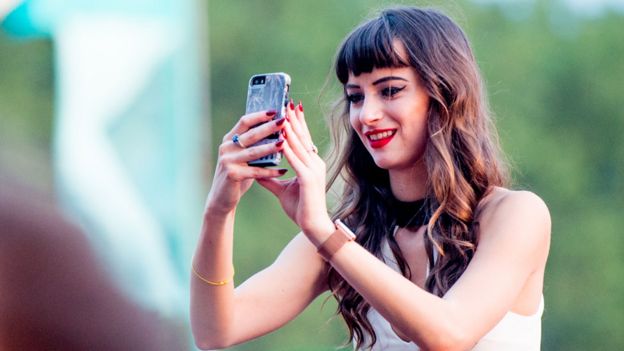 Adolescente con un celular usando Snapchat