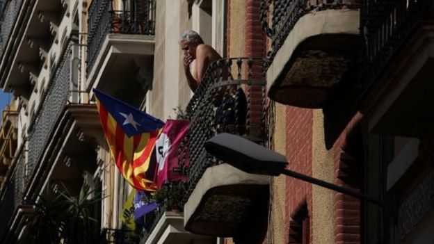 A Catalan separatist flag hangs from a balcony as a man smokes in Barcelona, Spain October 11, 2017
