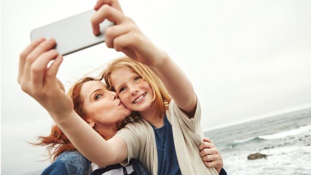 niña y madre usando celular