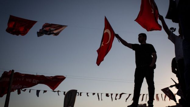 Gösterilerde bir kişi Türk bayrağı sallıyor.