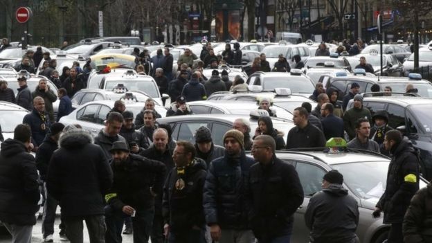 Striking French taxi drivers block the road as they protest about competition from private car-ride firms like Uber, in Paris (27 January 2016)
