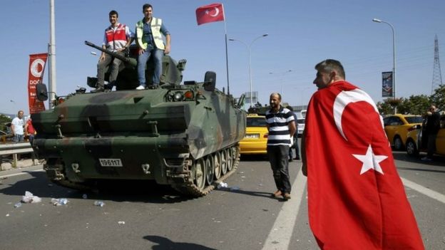 People stand on top of a military armoured vehicle after troops involved in the coup surrendered on the Bosphorus Bridge in Istanbul, Turkey. Photo: 16 July 2016