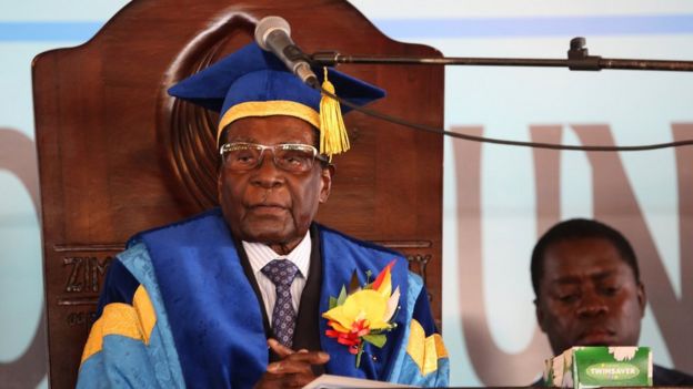 Mr Mugabe in wooden high-backed chair with microphone in front of him but above his mouth level