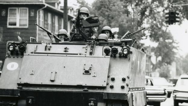 An image of a US Army tank patrolling through the streets of Detroit in 1967.