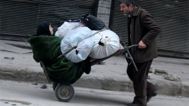 A man pushes a cart carrying an elderly woman and belongings as they flee deeper into the remaining rebel-held areas of Aleppo, Syria December 12, 2016