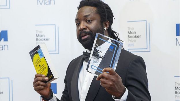 Escritor Marlon James muestra su libro y el premio que consiguió.