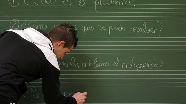 Hombre escribe en español en una pizarra.