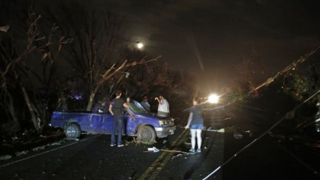 Uprooted trees and power lines litter the area as people a damaged vehicle in Rowlett, Texas. Photo: 26 December 2015