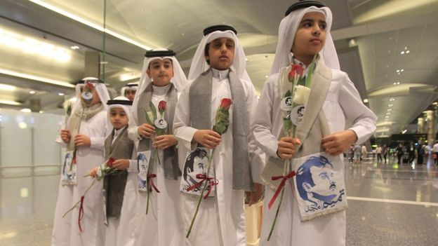 أطفال قطريون يحملون صورة الأمير القطري
