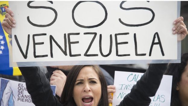 Una mujer con un cartel que dice SOS Venezuela