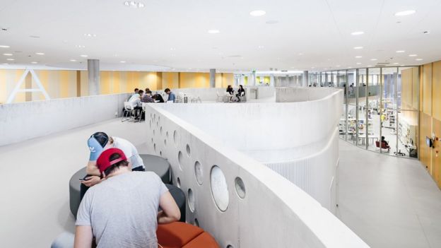 Estudiantes trabajan en un espacio abierto en una escuela finlandesa, con mobiliario ajustable.