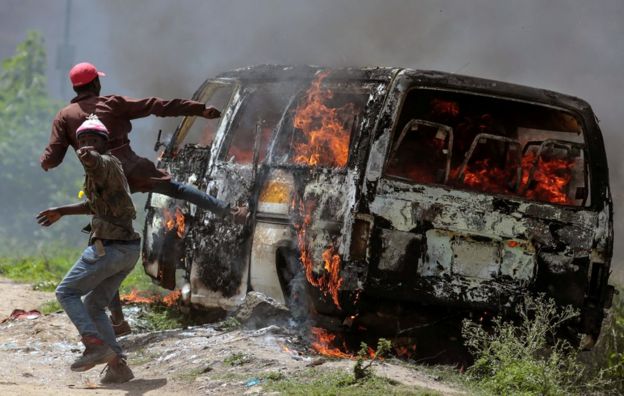 Supporters of the Kenyan opposition gesture near a burning vehicle in Embakasi, on the outskirts of Nairobi, Kenya, 28 November