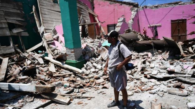 Man surveys damage to collapsed houses