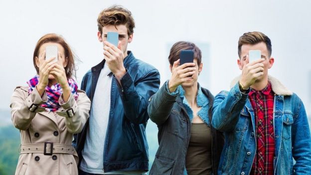 Cuatro jóvenes a quienes no se les ve el rostro, tapado por sus teléfonos