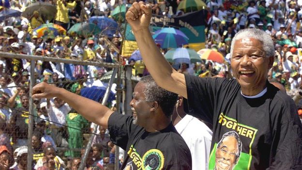 South African President Nelson Mandela (R) and deputy President Thabo Mbeki (L) greets the crowd from a pick-up truck during an African National Congress rally at the Orlando stadium in Soweto, 28 March 1999.