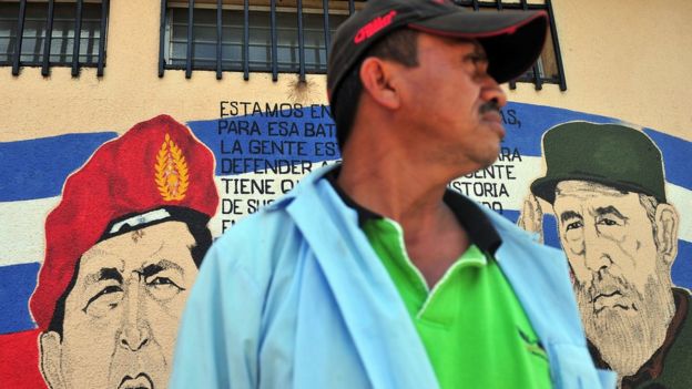Un hombre frente a un mural con los rostros de Hugo Chávez y Fidel Castro en Nicaragua.