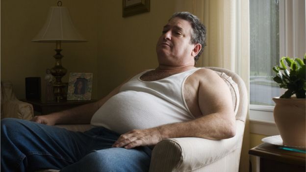 Homem obeso sentado no sofá