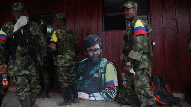 Un Alfonso Cano recortado en cartón observa a los guerrilleros recién llegados.