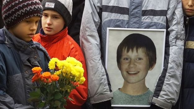 Мальчик с цветами и портретом погибшего ребенка