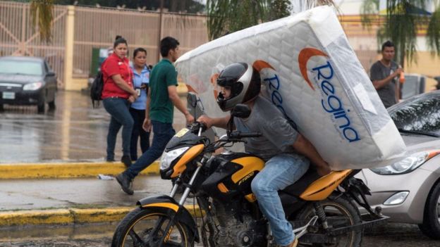 un hombre se lleva un colchón en una moto en Honduras
