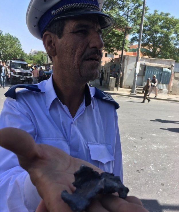 Un policía muestra a nuestro corresponsal un pedazo de metralla de la explosión
