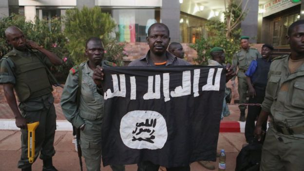 Malian security officials show a jihadist flag they said belonged to attackers in front of the Radisson hotel in Bamako.