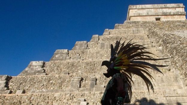 Un personaje vestido en un traje indígena prehispánico camina frente a la pirámide de Kukulkán, en el parque arqueológico de Chichén Itzá (20 diciembre, 2012)