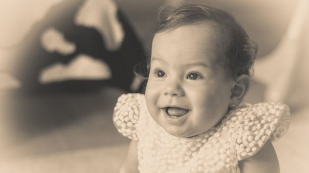 Una bebé sonriendo, en una foto antigua