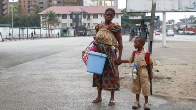 Mujer toma de la mano a su hijo que porta una mochila