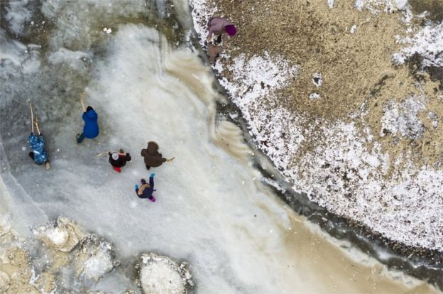 A picture taken with a drone shows children playing ice hockey with wood sticks on an icy patch by the frozen shore of the Lake of Neuchatel, in Yverdon-les-Bains, Switzerland, 28 February 2018