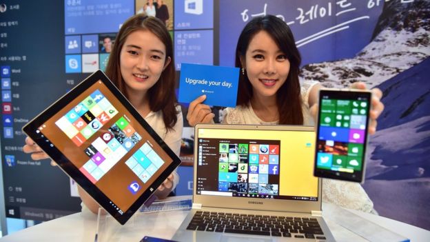 Dos mujeres muestran el sistema Windows en diferentes dispositivos