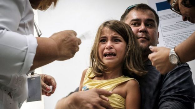 Девочка с ужасом взирает на шприц в руке врача