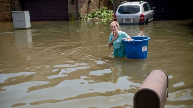 Jenna Fountain carries a bucket down flooded Regency Drive in Port Arthur, Texas, September 1, 2017