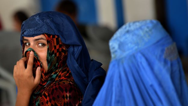 Una joven con el rostro descubierto junto a una mujer con una burka en el centro de repatriación de la ONU en Peshawar