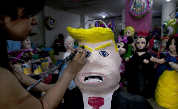 Mujer pinta una piñata de Donald Trump en México.