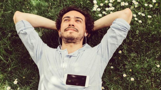 شخص مستلق على أرض خضراء ويفكر وهو مبتسم