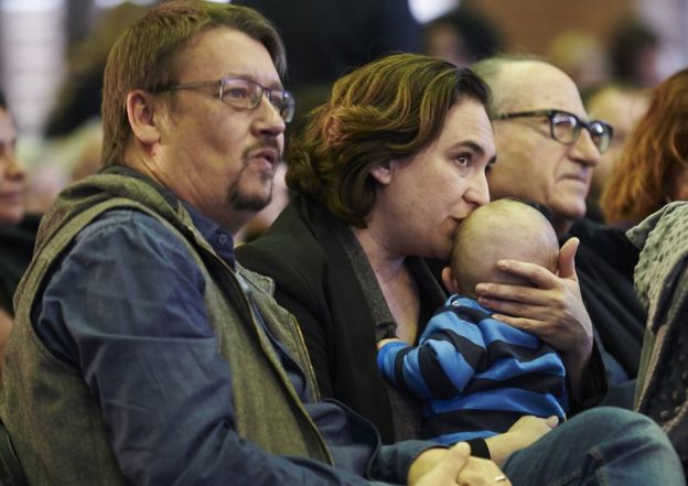 Ada Colau kisses her baby next to Xavier Domenech in Barcelona, 11 November