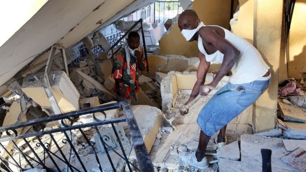Homem busca por sobreviventes em escombros de terremoto no Haiti em 2010
