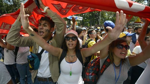 Manifestantes levantan una pancarta y marchan contra el gobierno de Nicolás Maduro en 2014.