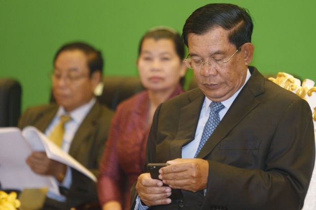 Cambodian Prime Minister Hun Sen checks his phone