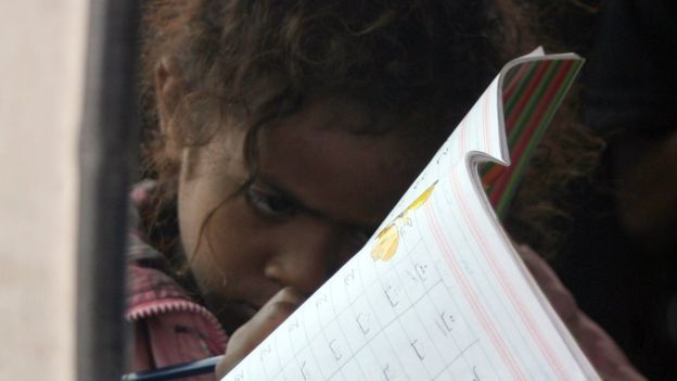 Una niña yemení lee un libro de texto.