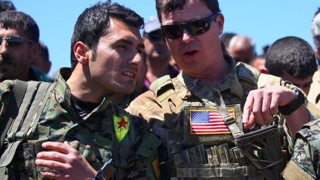 Thisfile photo taken on April 25, 2017 shows a US officer, from the US-led coalition, speaking with a fighter from the Kurdish People