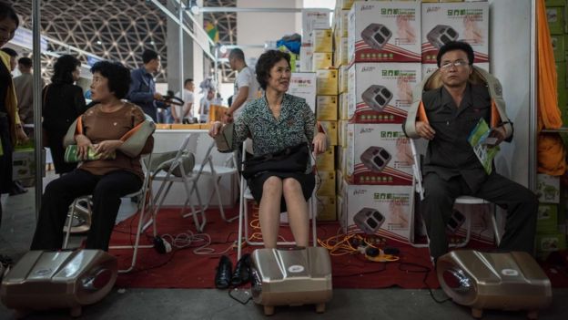 Norte-coreanos testam massageadores no estande da China em feira realizada em Pyongyang