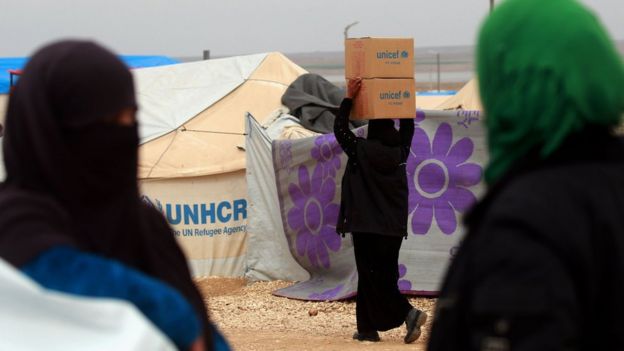 A woman carries boxes of humanitarian aid supplied by Unicef at a refugee camp in Syria's north-eastern Hassakeh province on February 26, 2018