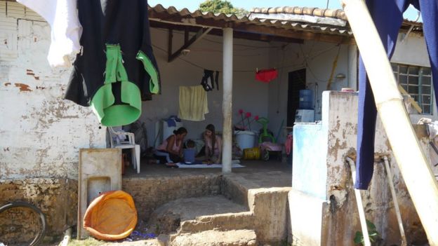 Mãe, criança e visitadora do Criança Feliz, sentadas no chão na varanda da casa (foto: Amanda Rossi/BBC Brasil)