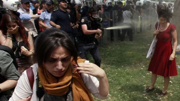 Una mujer vestida de rojo enfrenta a la policía en Turquía.