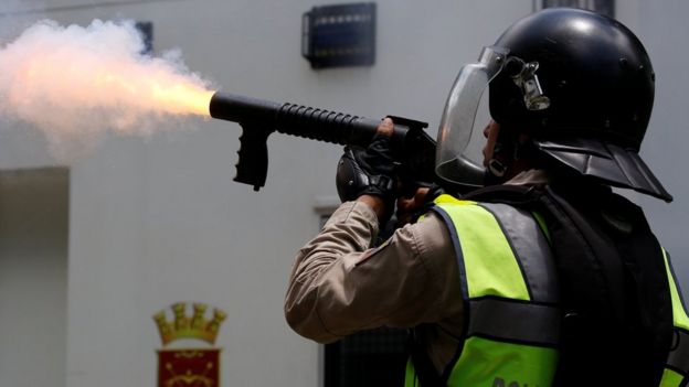 Policía disparando un cartucho de gas lacrimógeno.